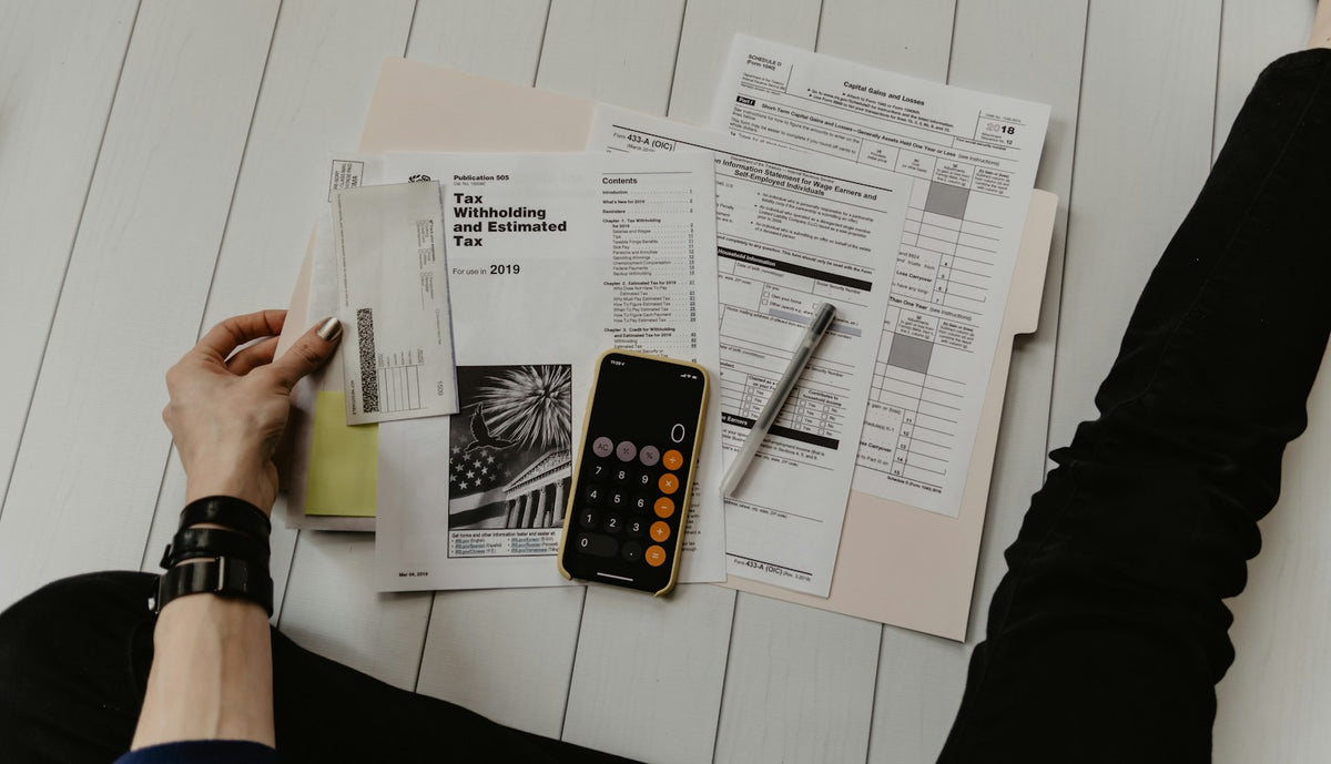 Person holding paperwork next to a calculator