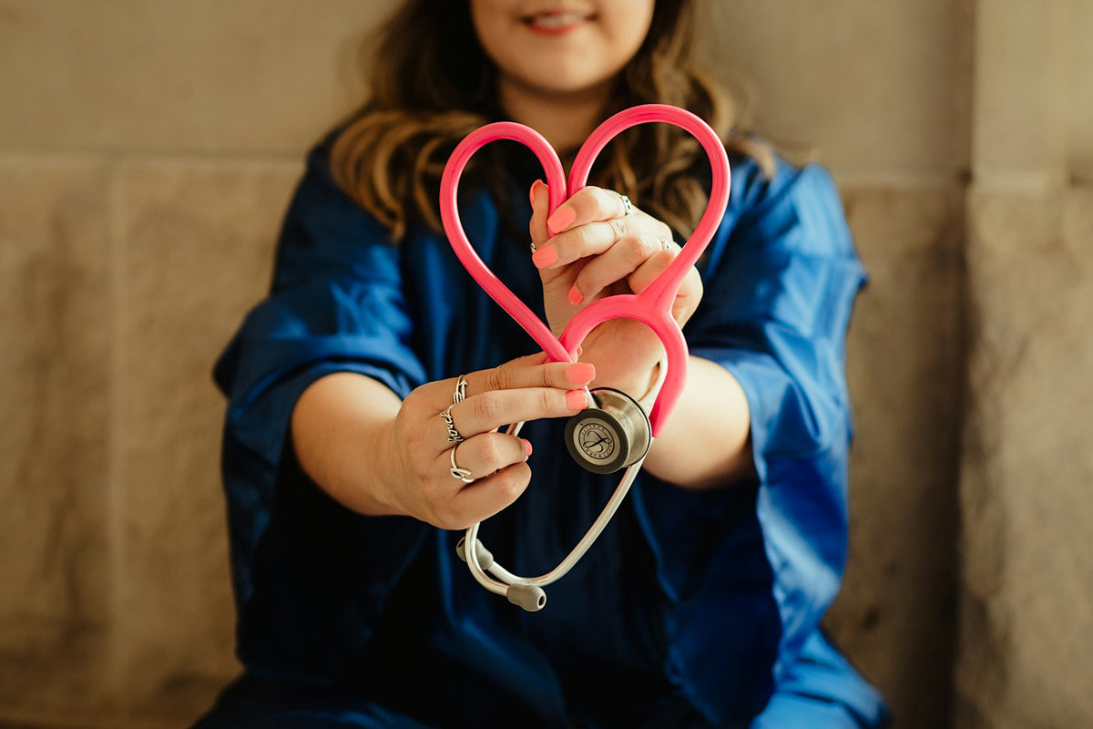 Nurse in scrubs holding a heart-shaped stethoscope